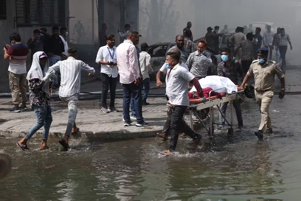 Pessoas carregam o corpo de uma vítima da queda de um avião da Air India em Ahmedabad - Foto: Amit Dave/Reuters