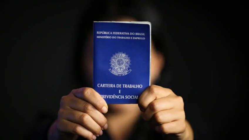 Na imagem, mulher segura carteira de trabalho com as duas mãos - Foto: Reprodução/Sérgio Lima