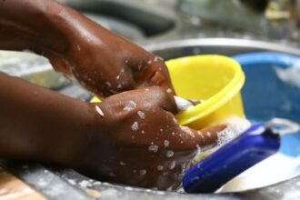 Mulher lavando louça e realizando atividades domésticas - Foto: Reprodução/Freepik