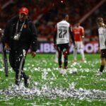 Funcionários do Beira-Rio usam rede para retirar papéis picados do gramado de Inter x Flamengo - Foto: Silvio Avila/AFP
