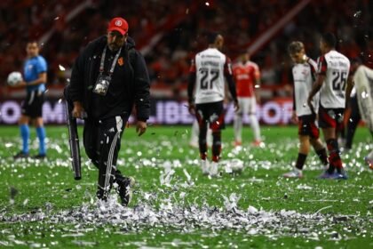 Funcionários do Beira-Rio usam rede para retirar papéis picados do gramado de Inter x Flamengo - Foto: Silvio Avila/AFP