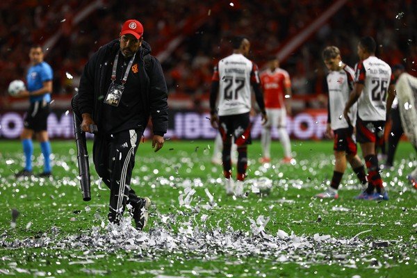 Funcionários do Beira-Rio usam rede para retirar papéis picados do gramado de Inter x Flamengo - Foto: Silvio Avila/AFP