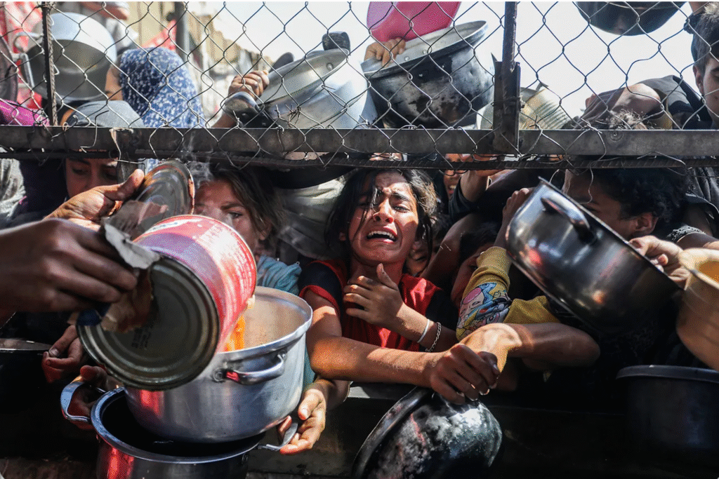  Meninas palestinas se aglomeram para receber porções de comida de uma cozinha comunitária em um campo de refugiados em Khan Younis, no sul da Faixa de Gaza, na sexta-feira, 30 de maio de 2025. Keystone-SDA