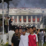 Selfie de jovens diante do palácio do governo do Nepal em chamas, em 9 de setembro de 2025 - Foto: AP Photo/Niranjan Shrestha