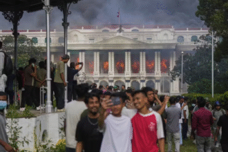 Selfie de jovens diante do palácio do governo do Nepal em chamas, em 9 de setembro de 2025 - Foto: AP Photo/Niranjan Shrestha