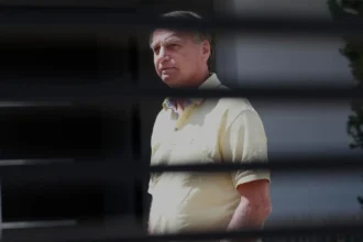 O ex-presidente do Brasil, Jair Bolsonaro, aparece na porta de sua casa, durante sua prisão domiciliar, em Brasília, Brasil, em 21 de novembro - Foto: Sebastião Moreira/EFE