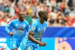 O atacante da República Democrática do Congo, Yoane Wissa (nº 20), cabeceia a bola e marca o primeiro gol de sua equipe durante a partida de futebol contra Portugal pelo Grupo K da Copa do Mundo de 2026, no Houston Stadium, em Houston (Foto: Ronaldo Schemidt / Afp)